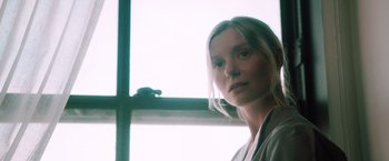 Movie still from “Shelter in Place” (2021), directed by Connor Martin – A woman standing in front of a window; Close Up shot, Low angle