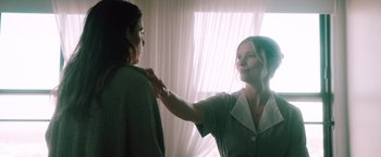 Movie still from “Shelter in Place” (2021), directed by Connor Martin – A woman standing next to another woman in front of a window; Medium shot, Over the shoulder angle