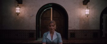 Movie still from “Shelter in Place” (2021), directed by Connor Martin – A woman sitting in front of an arched doorway; Medium shot, Low angle