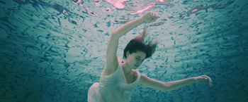 Movie still from “Shelter in Place” (2021), directed by Connor Martin – A woman swimming in a body of water; Medium shot, High angle