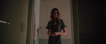 Movie still from “Shelter in Place” (2021), directed by Connor Martin – A woman in a green dress standing in front of a door; Medium shot, Low angle