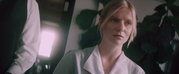 Movie still from “Shelter in Place” (2021), directed by Connor Martin – A woman wearing a white shirt and a blue necklace; Close Up shot, Low angle