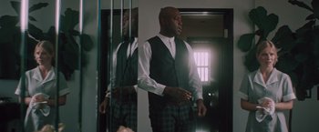 Movie still from “Shelter in Place” (2021), directed by Connor Martin – A man standing in front of a mirror holding a game controller; Medium shot, Low angle