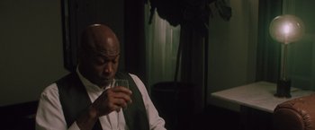 Movie still from “Shelter in Place” (2021), directed by Connor Martin – A man in a white shirt and a tie holding a wine glass; Medium shot, Low angle