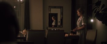 Movie still from “Shelter in Place” (2021), directed by Connor Martin – A woman standing in front of a mirror in a dark room; Wide shot, Over the shoulder angle