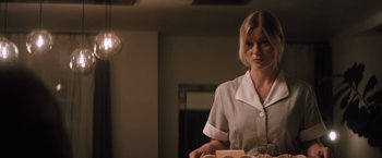 Movie still from “Shelter in Place” (2021), directed by Connor Martin – A woman standing in front of a mirror holding a tray; Medium shot, Low angle