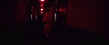 Movie still from “Shelter in Place” (2021), directed by Connor Martin – A woman walking down a hallway in a dark room; Wide shot, Low angle