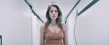 Movie still from “Shelter in Place” (2021), directed by Connor Martin – A woman in a tan tank top standing in a hallway; Close Up shot, Low angle