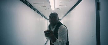 Movie still from “Shelter in Place” (2021), directed by Connor Martin – A man holding a video game controller in an elevator; Medium shot, Low angle