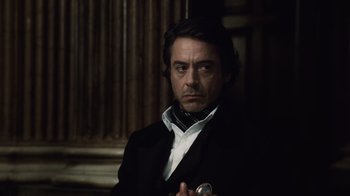 Movie still from “Sherlock Holmes” (2009), directed by Guy Ritchie – A person wearing a suit and tie; Close Up shot, Over the shoulder angle