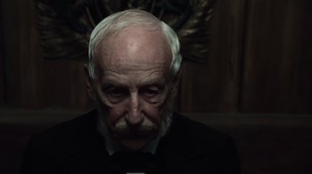 Movie still from “Sherlock Holmes” (2009), directed by Guy Ritchie – An old man with a beard and mustache wearing a black suit; Close Up shot, Low angle
