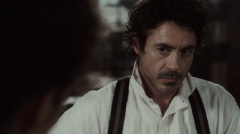 Movie still from “Sherlock Holmes” (2009), directed by Guy Ritchie – A person wearing a white shirt and suspenders; Close Up shot, Over the shoulder angle