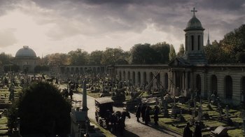 Movie still from “Sherlock Holmes” (2009), directed by Guy Ritchie – A cemetery with a horse drawn carriage and people walking around it; Extreme Wide shot, High angle