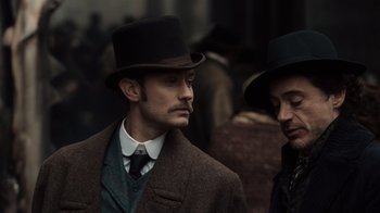 Movie still from “Sherlock Holmes” (2009), directed by Guy Ritchie – A man in a top hat standing next to another man in a suit; Close Up shot, Low angle