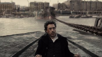 Movie still from “Sherlock Holmes” (2009), directed by Guy Ritchie – A man sitting on a boat in the middle of a river; Medium shot, High angle