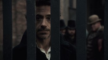 Movie still from “Sherlock Holmes” (2009), directed by Guy Ritchie – A person behind a fence; Close Up shot, Over the shoulder angle