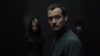 Movie still from “Sherlock Holmes” (2009), directed by Guy Ritchie – A man and a woman standing next to each other in a dark room; Close Up shot, Low angle