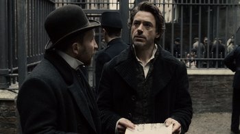 Movie still from “Sherlock Holmes” (2009), directed by Guy Ritchie – Two men standing next to each other on the street; Medium shot, Over the shoulder angle