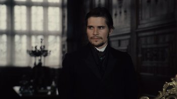 Movie still from “Sherlock Holmes” (2009), directed by Guy Ritchie – A man wearing a suit and tie standing in front of a window; Close Up shot, Over the shoulder angle