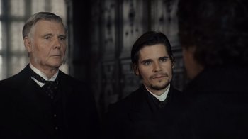 Movie still from “Sherlock Holmes” (2009), directed by Guy Ritchie – A man in a suit and tie standing next to another man in a suit and tie; Close Up shot, Over the shoulder angle