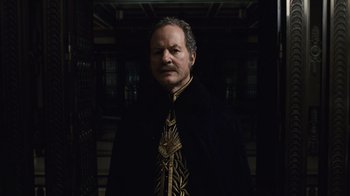 Movie still from “Sherlock Holmes” (2009), directed by Guy Ritchie – An older man wearing a black coat and a gold tie; Close Up shot, Low angle