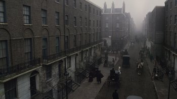 Movie still from “Sherlock Holmes” (2009), directed by Guy Ritchie – A street scene with a horse drawn carriage and people walking down the sidewalk; Extreme Wide shot, High angle