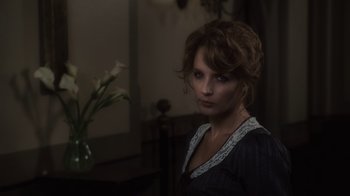 Movie still from “Sherlock Holmes” (2009), directed by Guy Ritchie – A woman in a dark room with a vase of flowers in front of her; Close Up shot, Over the shoulder angle