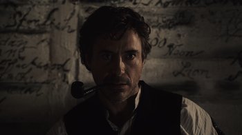 Movie still from “Sherlock Holmes” (2009), directed by Guy Ritchie – A man with a pipe in his mouth; Close Up shot, Over the shoulder angle