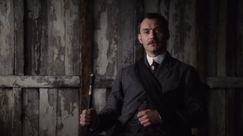Movie still from “Sherlock Holmes” (2009), directed by Guy Ritchie – A man in a suit and tie holding a baseball bat; Medium shot, Low angle