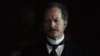 Movie still from “Sherlock Holmes” (2009), directed by Guy Ritchie – A man with a mustache wearing a suit and tie; Close Up shot, Low angle