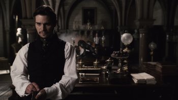 Movie still from “Sherlock Holmes” (2009), directed by Guy Ritchie – A man standing in front of a desk with other people in the background; Medium shot, Over the shoulder angle