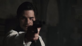 Movie still from “Sherlock Holmes” (2009), directed by Guy Ritchie – A man holding a gun pointed at the camera; Close Up shot, Over the shoulder angle