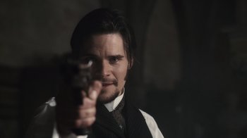 Movie still from “Sherlock Holmes” (2009), directed by Guy Ritchie – A man holding a gun pointed at the camera; Close Up shot, Over the shoulder angle