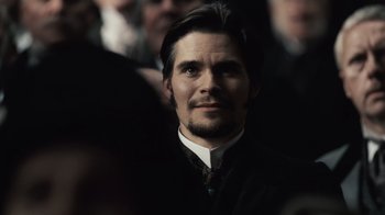 Movie still from “Sherlock Holmes” (2009), directed by Guy Ritchie – A person wearing a suit and tie; Close Up shot, Over the shoulder angle