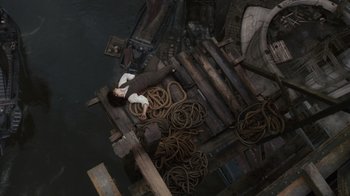 Movie still from “Sherlock Holmes” (2009), directed by Guy Ritchie – An aerial view of a woman laying on a dock; Extreme Wide shot, Overhead angle