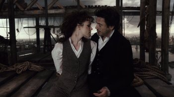 Movie still from “Sherlock Holmes” (2009), directed by Guy Ritchie – A man and a woman are kissing in front of a bridge; Medium shot, Low angle