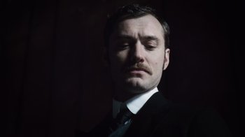 Movie still from “Sherlock Holmes” (2009), directed by Guy Ritchie – A man in a black suit and a black tie; Close Up shot, Low angle