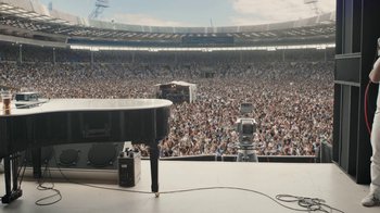 Movie still from “Bohemian Rhapsody” (2018), directed by Bryan Singer – A large crowd of people at an outdoor concert; Extreme Wide shot, High angle