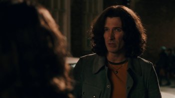 Movie still from “Bohemian Rhapsody” (2018), directed by Bryan Singer – A man with long dark hair is looking into the camera; Close Up shot, Over the shoulder angle