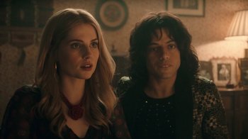 Movie still from “Bohemian Rhapsody” (2018), directed by Bryan Singer – A man and a woman standing next to each other in a room; Close Up shot, Over the shoulder angle