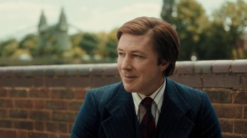 Movie still from “Bohemian Rhapsody” (2018), directed by Bryan Singer – A person wearing a suit and tie; Close Up shot, Over the shoulder angle