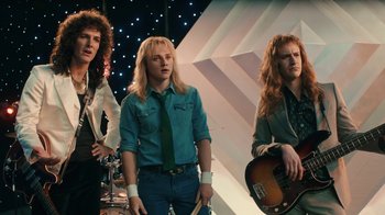 Movie still from “Bohemian Rhapsody” (2018), directed by Bryan Singer – A group of men standing next to each other; Medium shot, Low angle