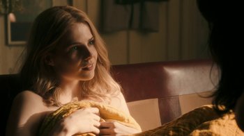 Movie still from “Bohemian Rhapsody” (2018), directed by Bryan Singer – A beautiful young lady sitting on a chair; Close Up shot, Over the shoulder angle