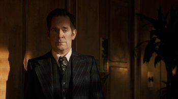 Movie still from “Bohemian Rhapsody” (2018), directed by Bryan Singer – A man wearing a suit and tie in a room; Medium shot, Low angle