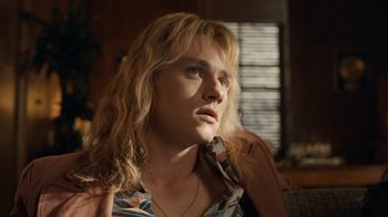 Movie still from “Bohemian Rhapsody” (2018), directed by Bryan Singer – A woman with long blonde hair wearing a colorful shirt; Close Up shot, Over the shoulder angle