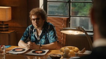 Movie still from “Bohemian Rhapsody” (2018), directed by Bryan Singer – An older man sitting at a table in front of a record player; Medium shot, Over the shoulder angle