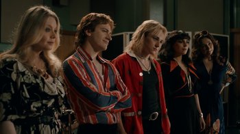 Movie still from “Bohemian Rhapsody” (2018), directed by Bryan Singer – A group of people standing next to each other in a room; Medium shot, Over the shoulder angle