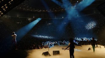 Movie still from “Bohemian Rhapsody” (2018), directed by Bryan Singer – A man playing a guitar in front of an audience in a stadium; Extreme Wide shot, High angle