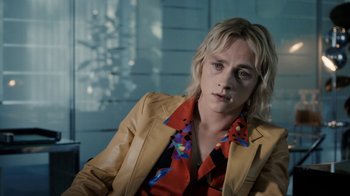 Movie still from “Bohemian Rhapsody” (2018), directed by Bryan Singer – A person with blonde hair wearing a yellow jacket; Close Up shot, Over the shoulder angle