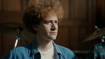 Movie still from “Bohemian Rhapsody” (2018), directed by Bryan Singer – A young man with red curly hair is looking to his left; Close Up shot, Over the shoulder angle